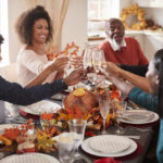 Multi generation mixed race family raise their glasses to make a toast at their Thanksgiving dinner table