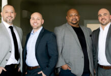 Four professional real estate brokers standing in business attire; from left to right are Jason Liberty, Tim Bower, Ameet Prasad, and Robert Covais